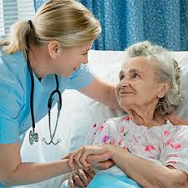 A nurse holds an older women's hand.